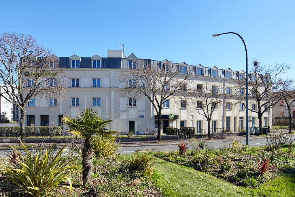 サン・モール・デ・フォッセにあるB&B HOTEL Saint-Maur Créteilの目の前に木々が植えられた白い大きな建物