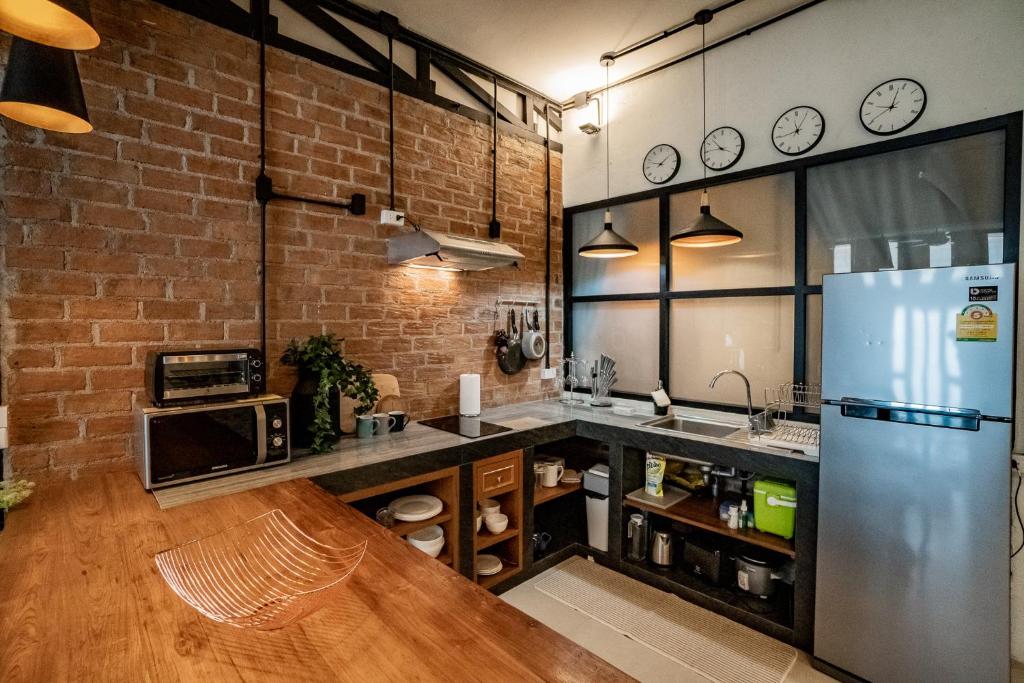 a kitchen with a refrigerator and a brick wall at Luxury Industrial Flat in the Heart of Chiang Mai in Chiang Mai