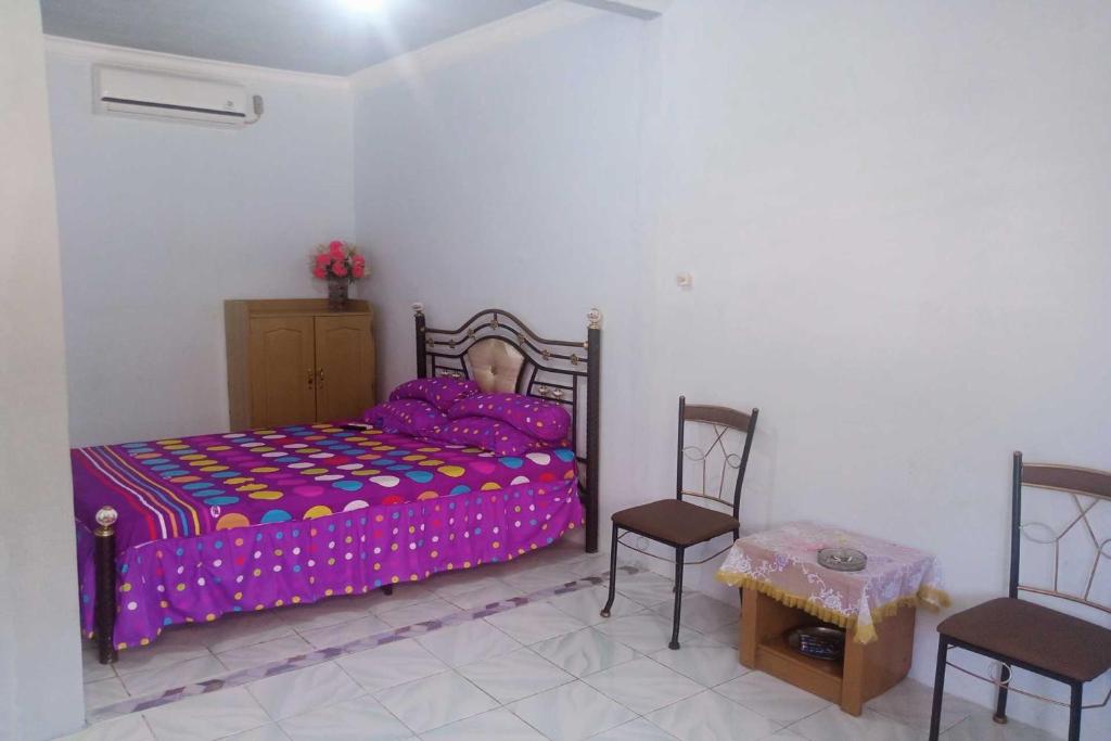 um quarto com uma cama, 2 cadeiras e uma mesa em EXPRESS O 92251 Jaya Kusuma Homestay em Jambi