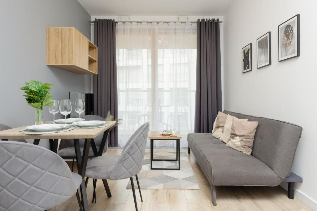 ein Wohnzimmer mit einem Esstisch und einem Sofa in der Unterkunft Cozy Apartments with Parking in the 19th District by Renters in Warschau