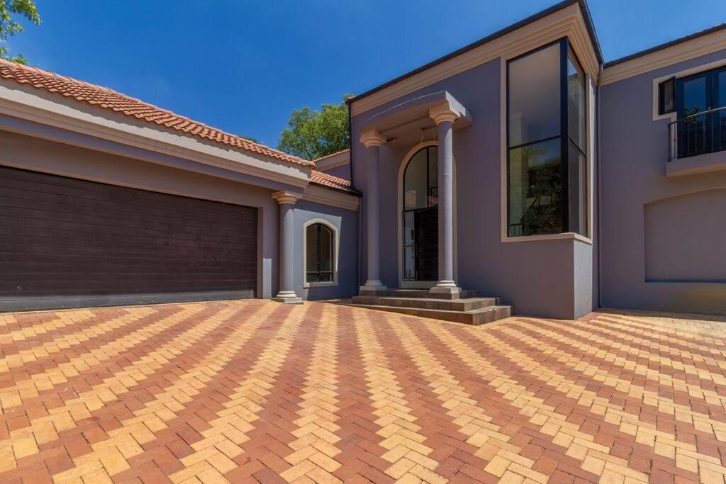 a house with a brick driveway in front of it at Lovely Family home in Bryanston in Johannesburg