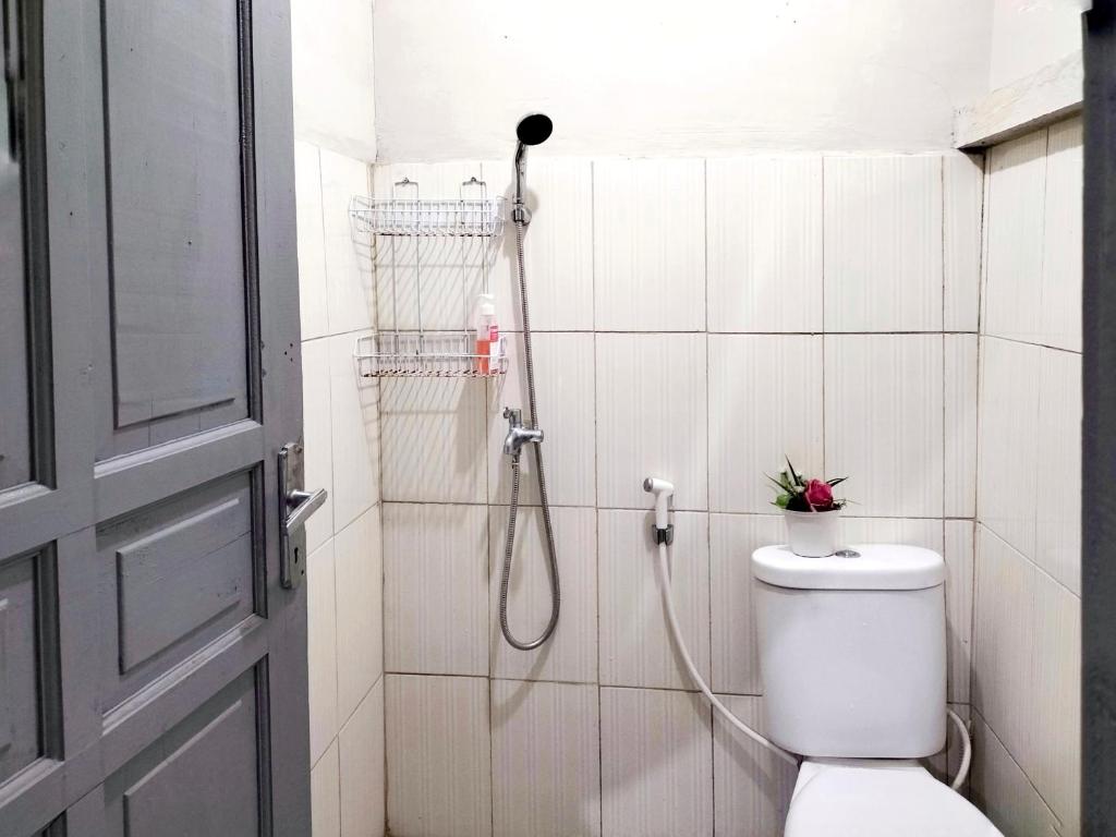 a bathroom with a shower with a toilet and a hose at Brussels Homestay Kost in Balige