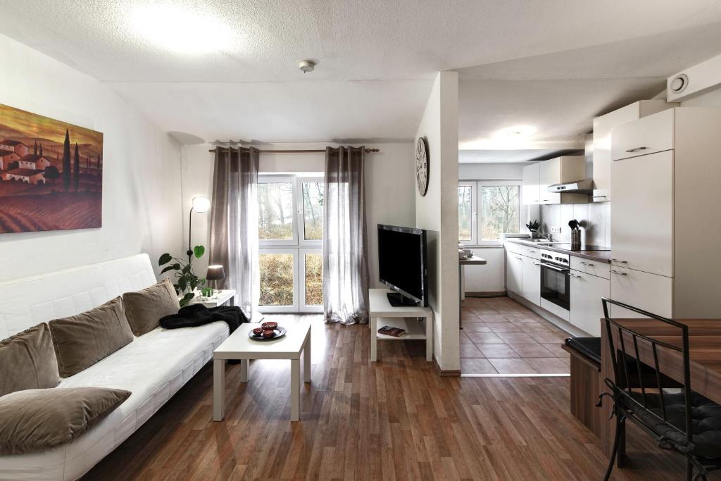 a living room with a white couch and a kitchen at Arkadia Haus Alstertal in Hamburg