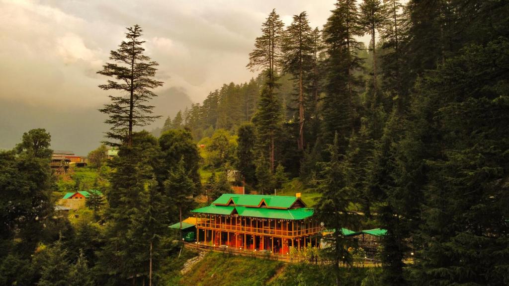 a building with a green roof in the middle of a forest at The Hosteller Shangarh, Sainj Valley in Sainj