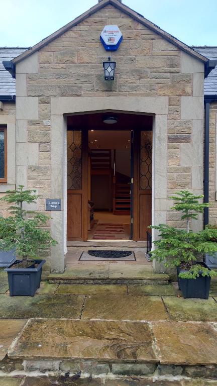 a building with a large wooden door and two potted trees at Rosebank Lodge in High Bentham