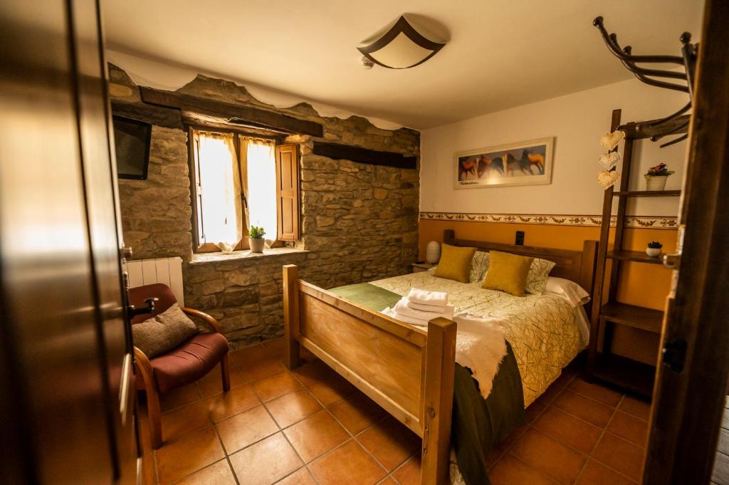 1 dormitorio con 1 cama, 1 silla y 1 ventana en La Borda de Pastores, en Sabiñánigo