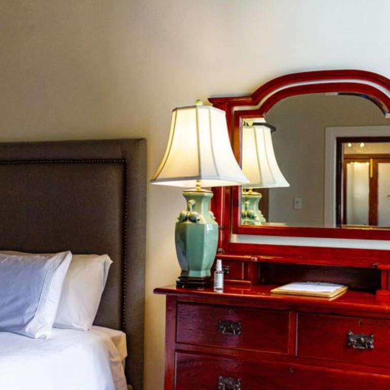 a bedroom with a red dresser with a lamp and a mirror at Plaisir Estate Accommodation in Simondium