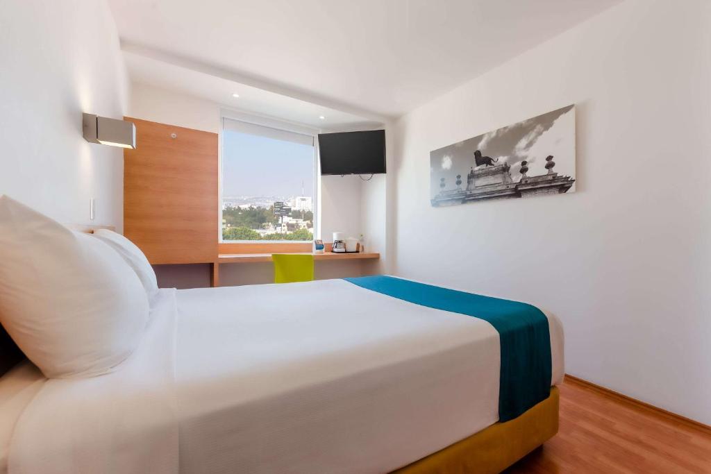 Un dormitorio con una gran cama blanca y una ventana en Sleep Inn Leon Antares, en León
