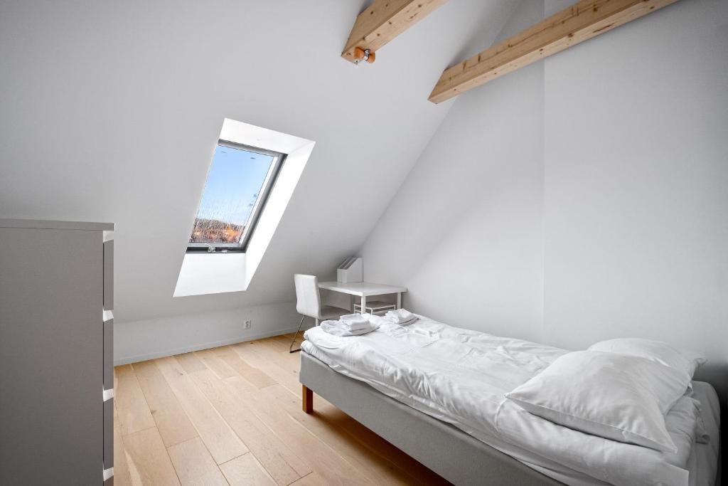 Habitación blanca con cama y ventana en Stay Bryggen - Serviced apartments in the city center, en Bergen