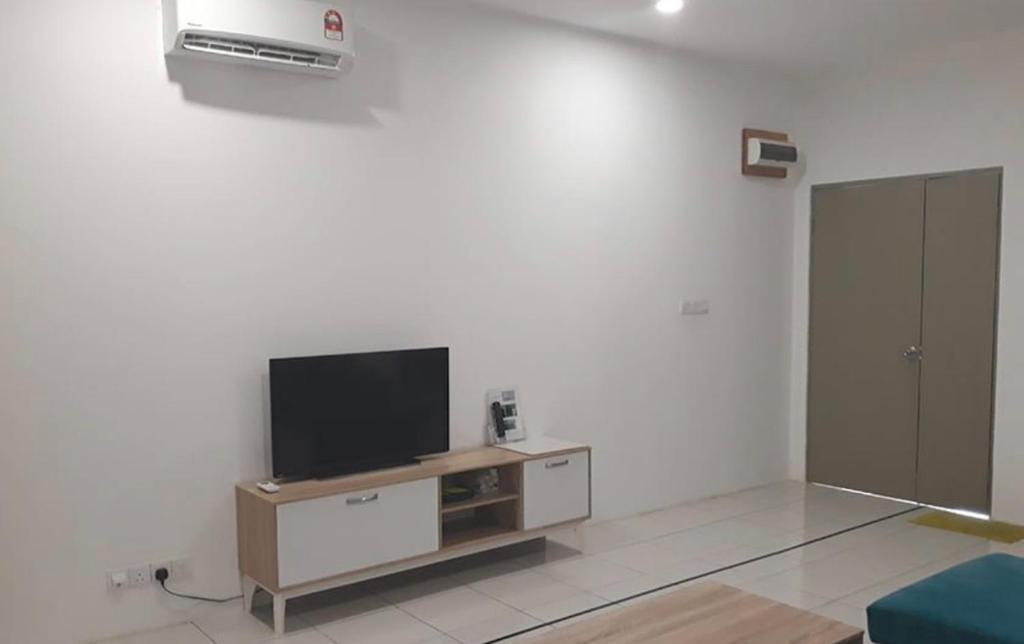 uma sala de estar com uma televisão de ecrã plano numa parede branca em Khayla’s Residence em Papar