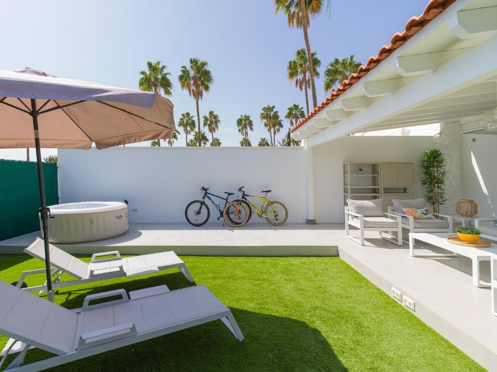 um pátio com espreguiçadeiras e um guarda-sol em Aquarium Bungalow private jacuzzi, 3 bedrooms, AC and Bikes em Maspalomas