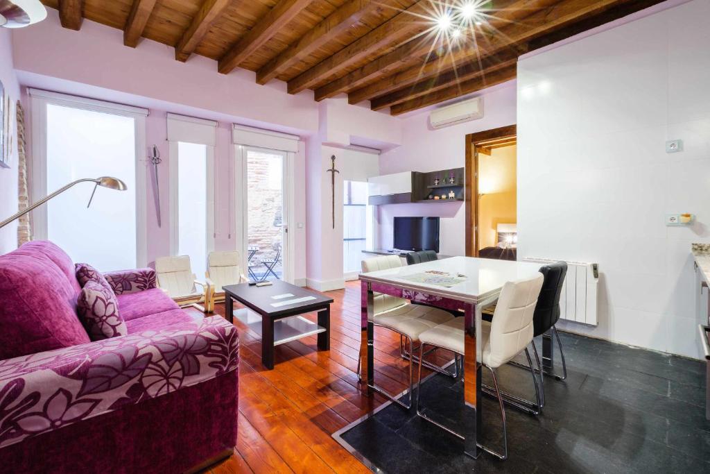 een woonkamer met een paarse bank en een tafel bij Apartamento con patio junto a la Catedral by Toledo AP in Toledo