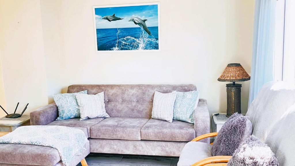 a living room with a couch and two birds in the air at Silverdunes - Seaview in Bettyʼs Bay