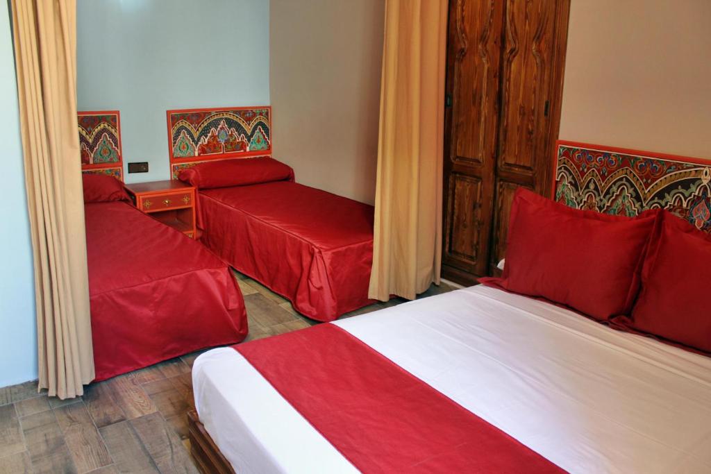 タンジェにあるホテル マラムのベッド2台と赤い枕が備わるホテルルームです。