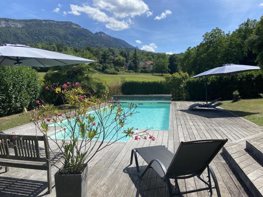 a swimming pool with two chairs and an umbrella at ST JORIOZ-Maison spacieuse avec PISCINE et Vue, LLA Selections by Location lac Annecy in Saint-Jorioz
