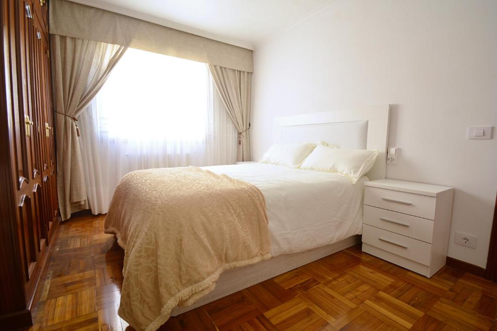 een witte slaapkamer met een bed en een raam bij Piso en pleno centro de Vilagarcía de Arousa in Vilagarcia de Arousa