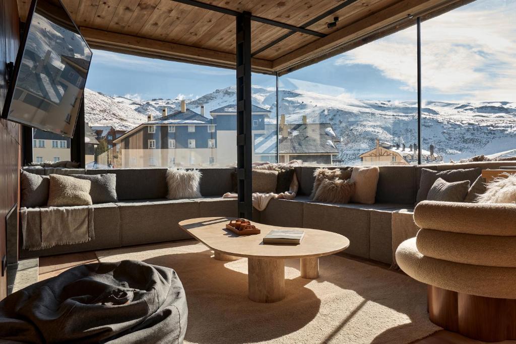 een woonkamer met een bank en een tafel bij AticoNevado - Apartamento de lujo con vistas panoramicas 360 in Sierra Nevada