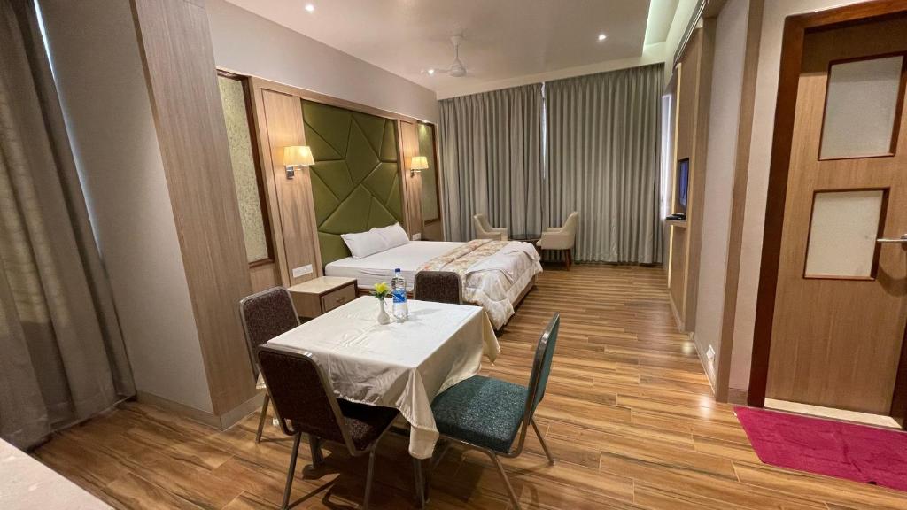 a hotel room with a bed and a table and chairs at Hotel Sarovar Residency in Boisar