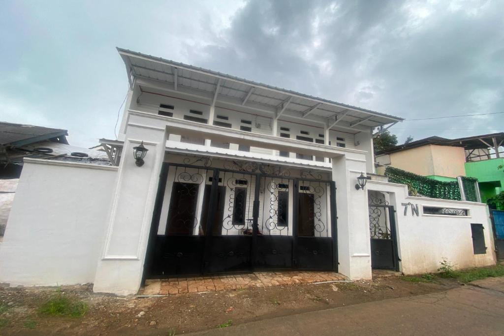 uma casa branca com portas negras numa rua em EXPRESS O 92147 Nia Residence em Depok