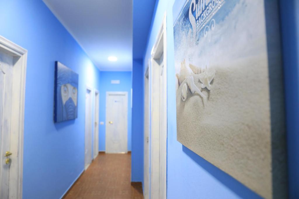 un couloir aux murs bleus et une peinture sur une plage dans l'établissement First Hostel Tropea, à Tropea