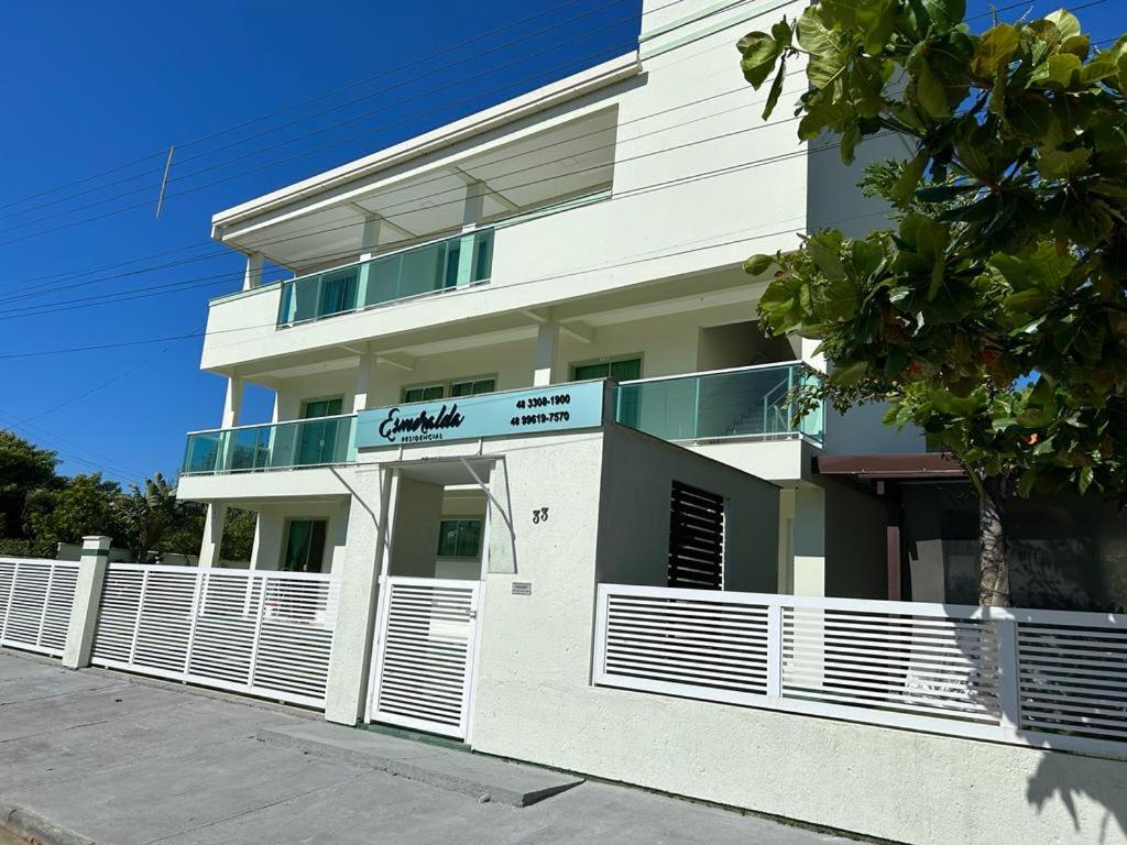 un edificio blanco con una valla delante en Residencial Esmeralda-Vista ao Mar, en Palhoça