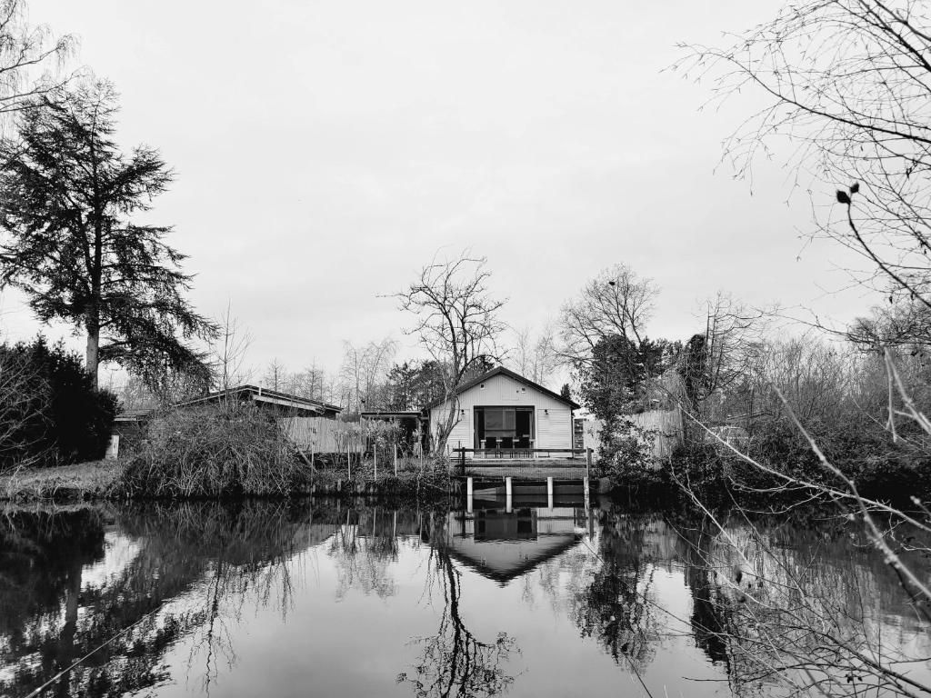 a house sitting on the side of a river at Rustig gelegen chalet Kapeki met tuin aan het water in Geel