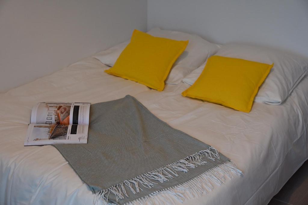 een bed met gele kussens en een tijdschrift erop bij Cosy Studio in Ivry-sur-Seine