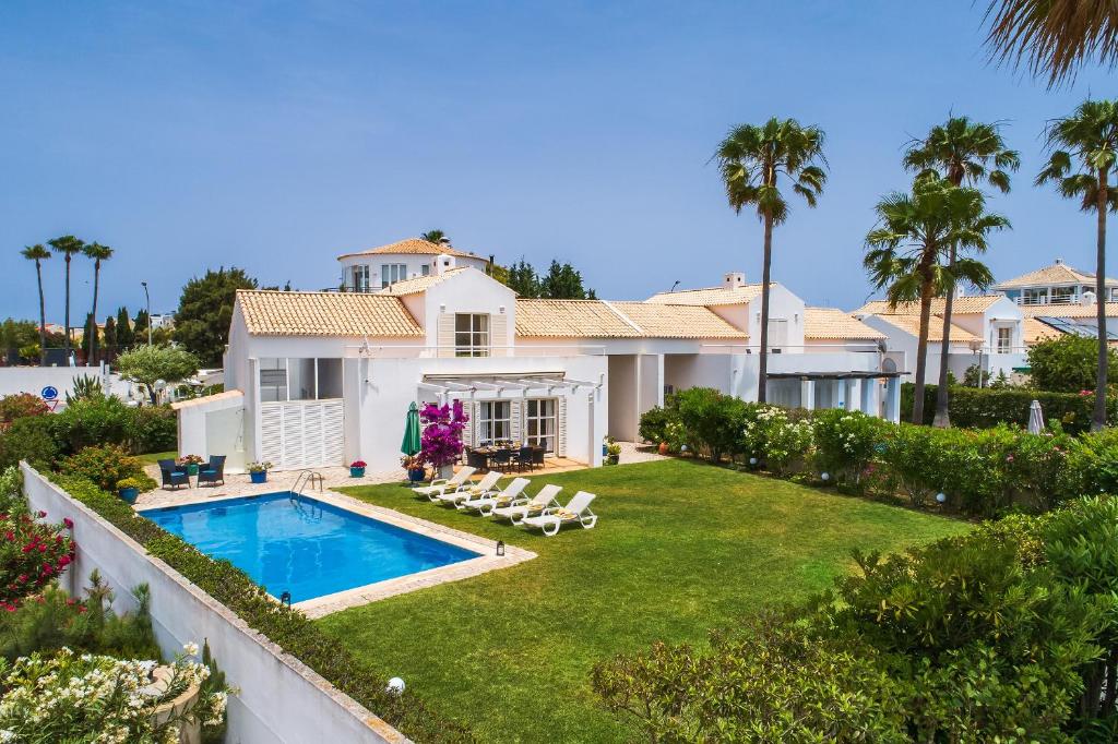 a house with a swimming pool and palm trees at Villa Farol by OCvillas in Galé