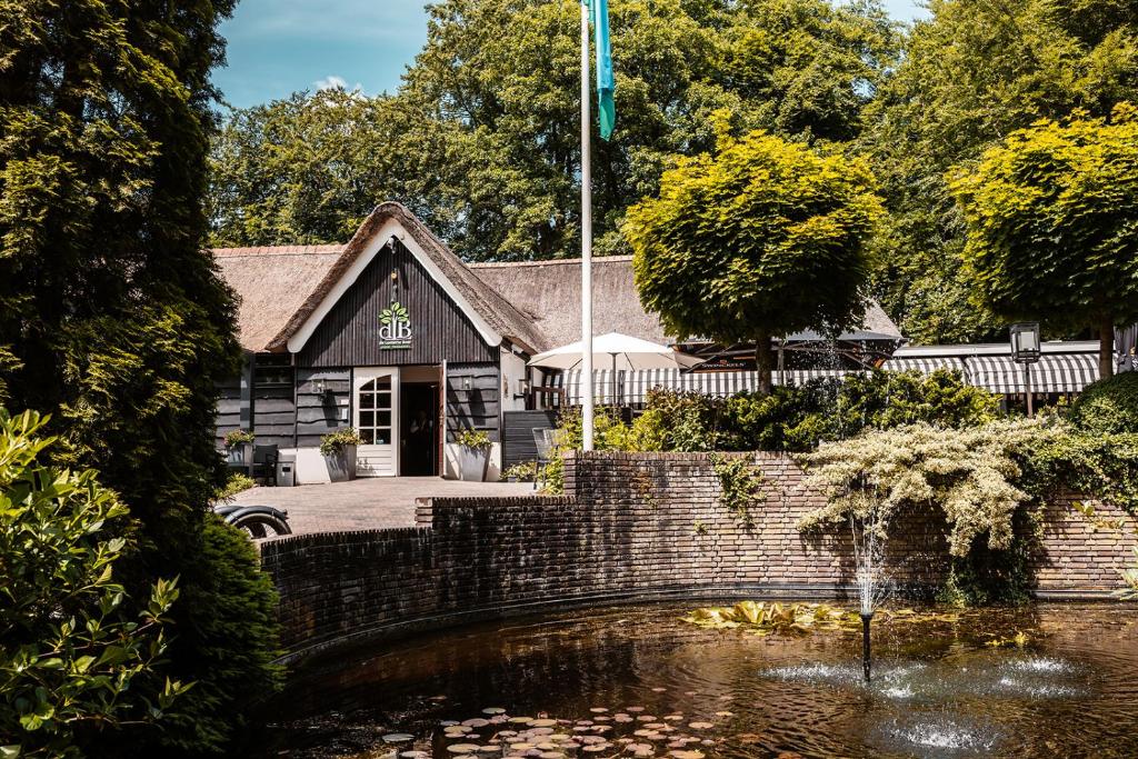 ein Haus mit einem Teich davor in der Unterkunft De Lunterse Boer in Lunteren