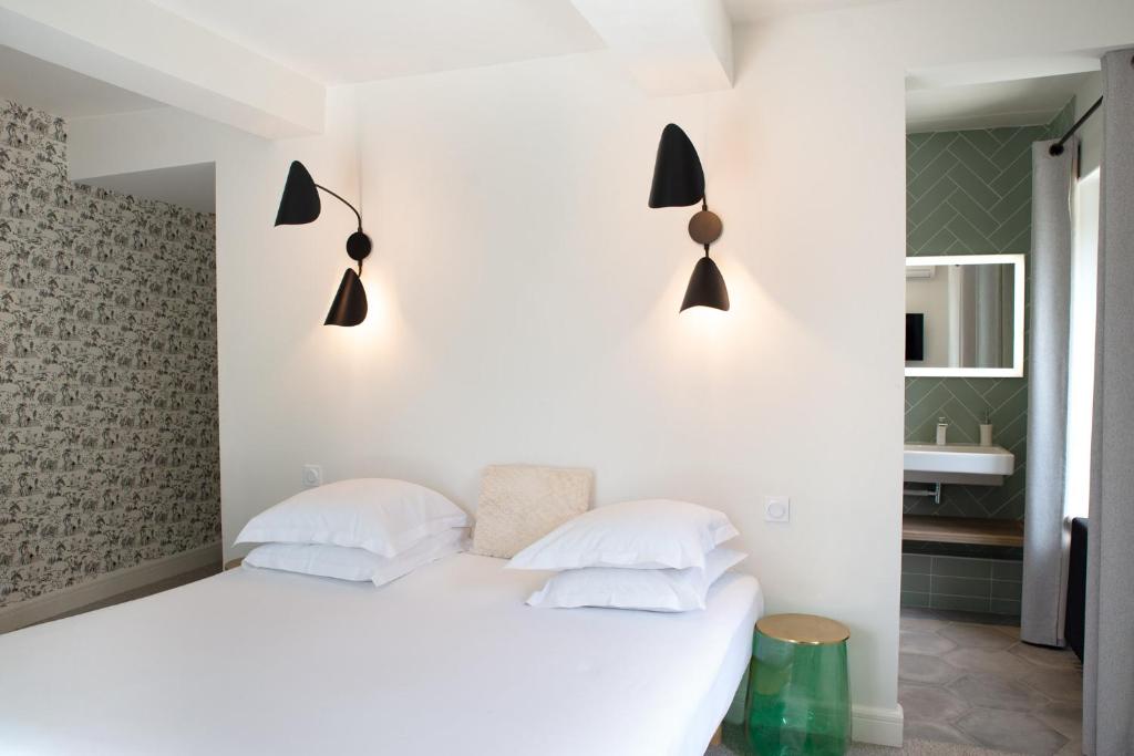 a bedroom with a white bed with three pillows at Manoir le Roure in Châteauneuf-du-Rhône