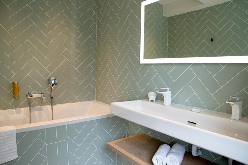 a bathroom with a sink and a tub and a mirror at Manoir le Roure in Châteauneuf-du-Rhône