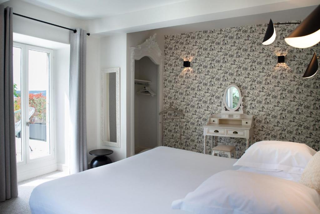 a bedroom with a white bed and a mirror at Manoir le Roure in Châteauneuf-du-Rhône