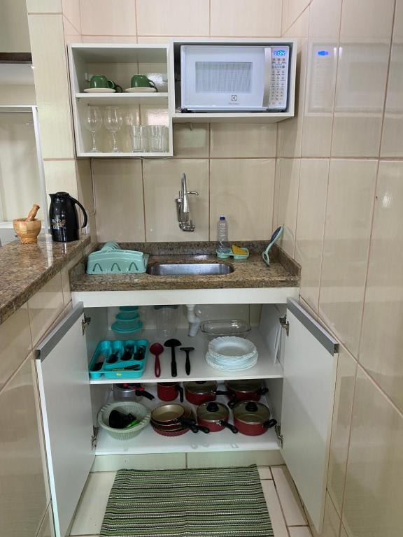 eine Küche mit einer Spüle und einer Mikrowelle in der Unterkunft Casa aconchegante e charmosa à 6 min da Praia - Ar condicionado - WIFI 600MB - Netflix - Globoplay - Cozinha Completa in Rio das Ostras