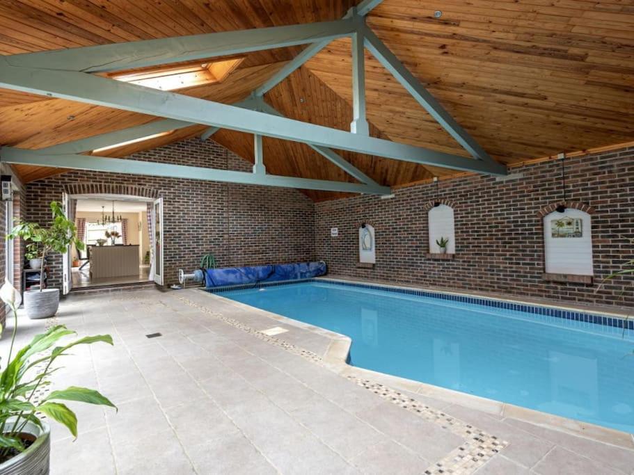 an indoor swimming pool with a wooden ceiling at Large coastal cottage, private indoor pool, hut tub, sauna and steam pod in Weymouth