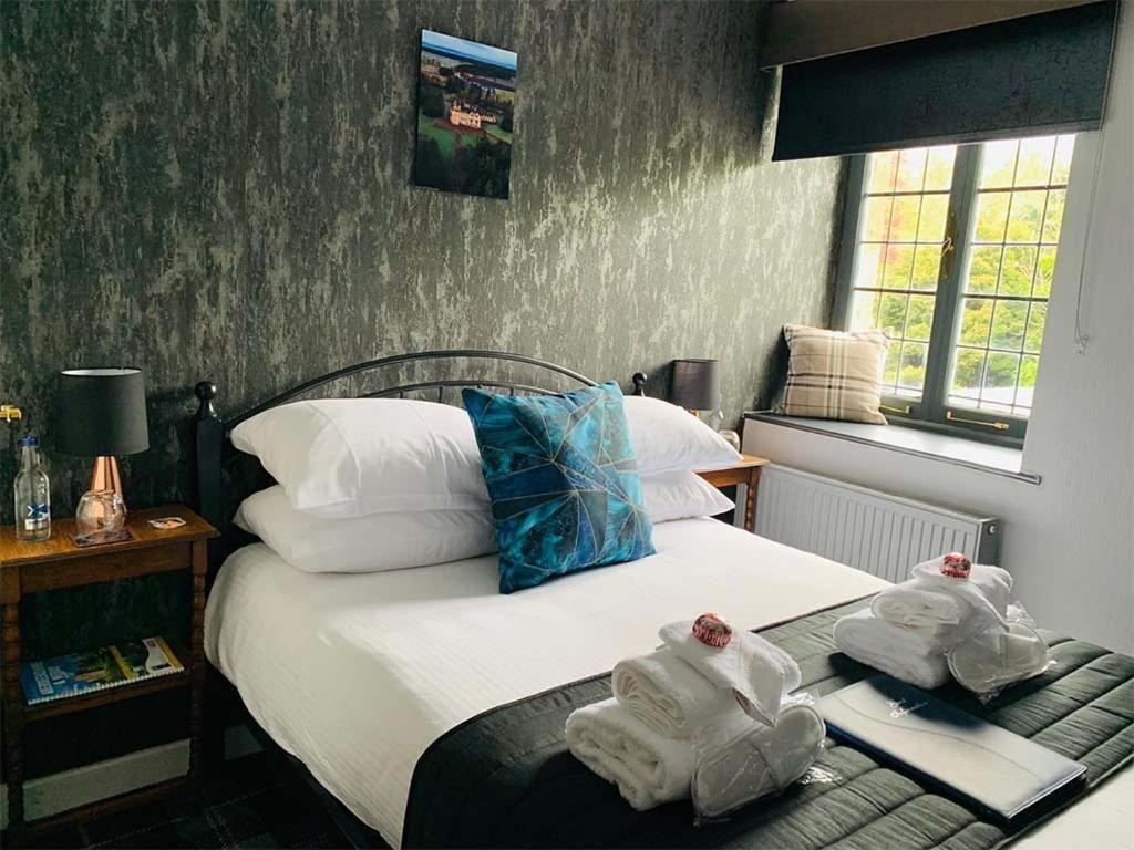 1 dormitorio con 1 cama con toallas en The Old Mill Inn, en Forres