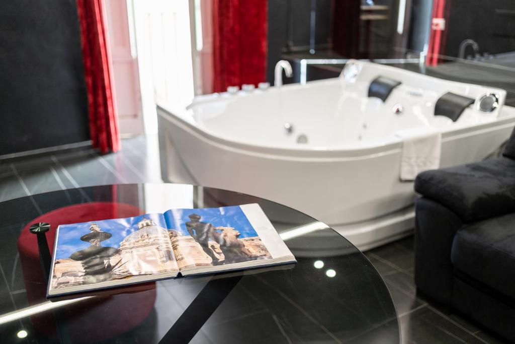 a bathroom with a tub and a table with a book at Marmur Suite in Palermo