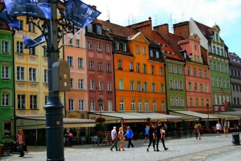 a group of people walking in a city with buildings at Cozy room - 10 min.from Rynek in Wrocław