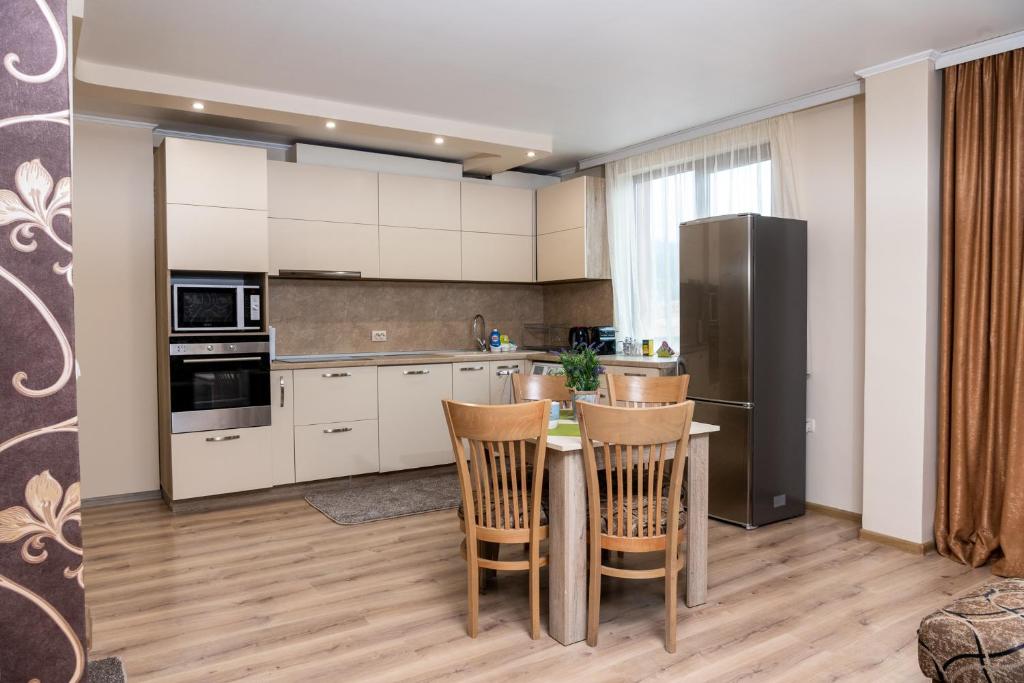 eine Küche mit weißen Schränken sowie einem Tisch und Stühlen in der Unterkunft Panorama Apartment in Welingrad