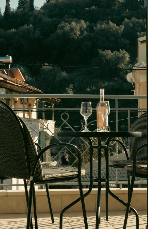 a table with two wine glasses on a balcony at Baia Blu Apartments in Syvota