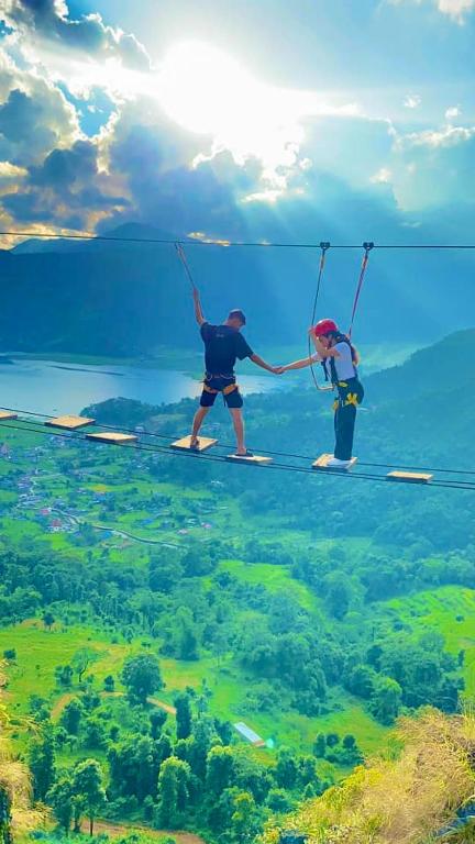 two people are holding hands while standing on a rope at Rock Garden Resort in Pokhara