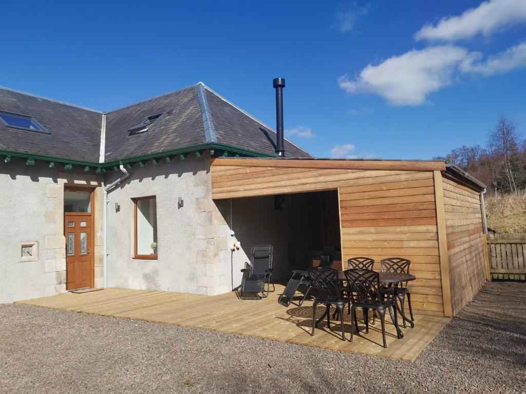 a building with a wooden deck with a table and chairs at The Stables with Hot Tub in Cray