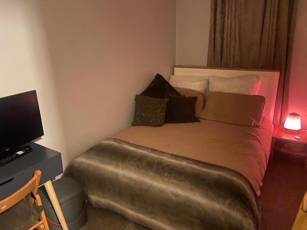 a bedroom with a bed and a desk with a television at Cozy home in Croydon