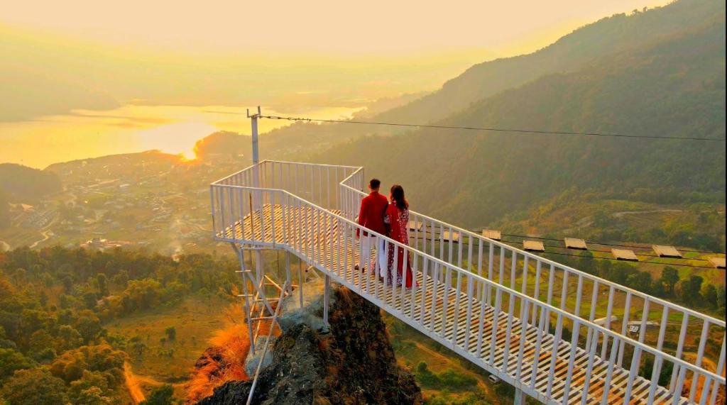 two people standing on a suspension bridge on top of a mountain at Rock Garden Resort in Pokhara