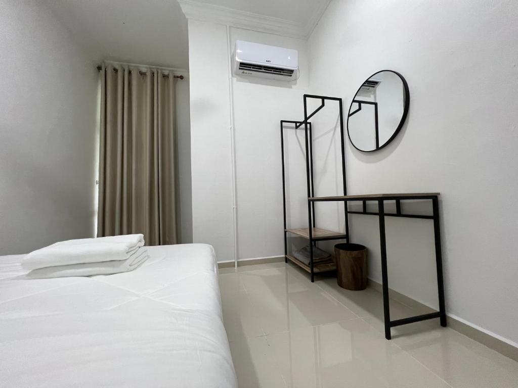 a white room with a bed and a mirror at Laena Homestay in Kangar