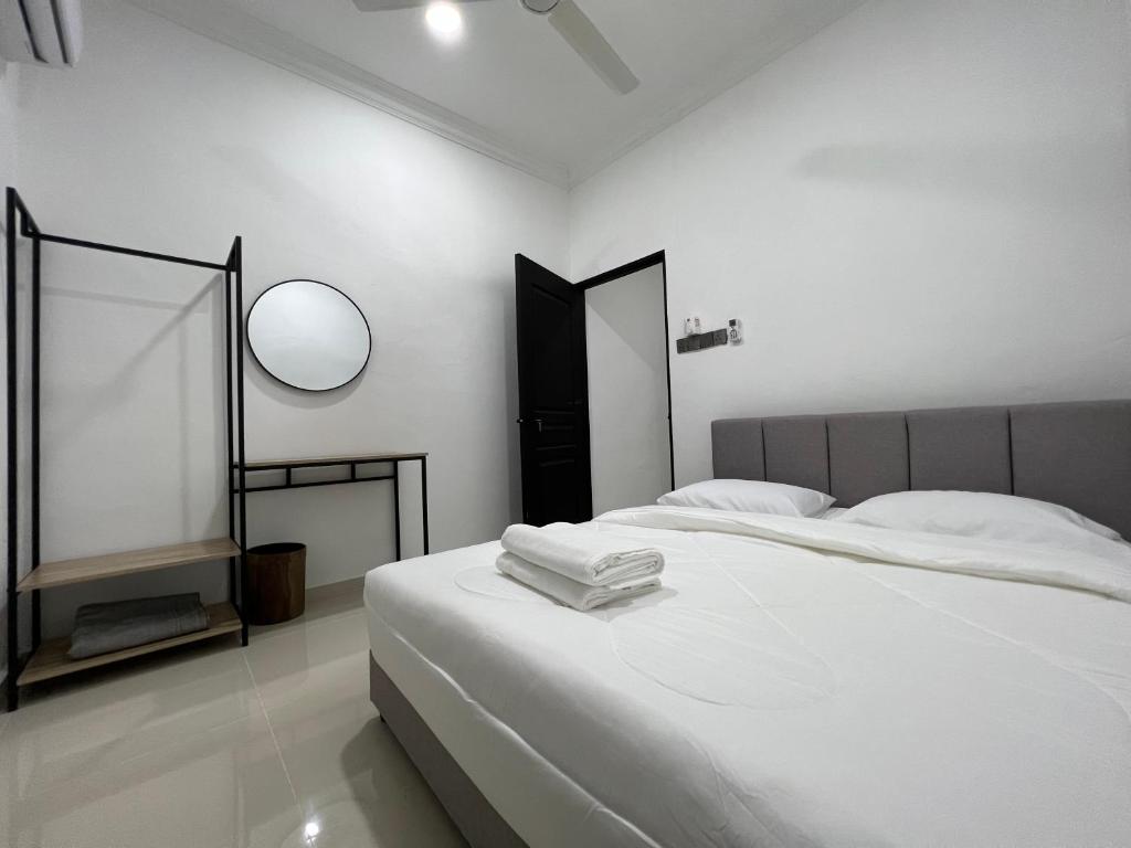 a white bedroom with a bed and a mirror at Laena Homestay in Kangar