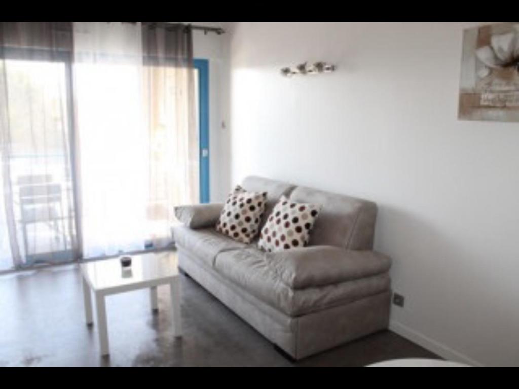 ein Wohnzimmer mit einem Sofa und einem Tisch in der Unterkunft Coquet studio classé trois étoiles in Balaruc-les-Bains