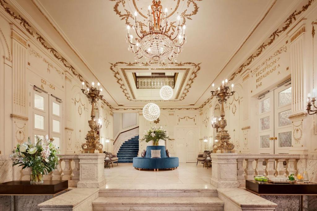 un grand hall avec un lustre et un escalier dans l'établissement Tivoli Doelen Amsterdam Hotel, à Amsterdam