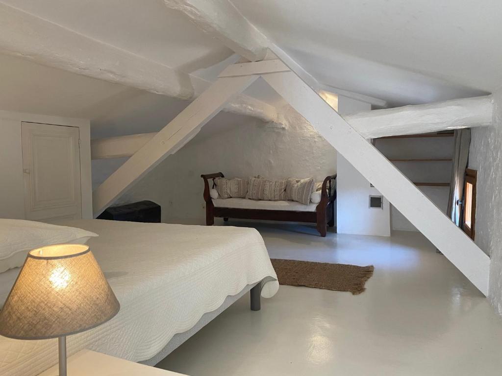 a white bedroom with a bed and a chair at Campagne Salettes in Lorgues