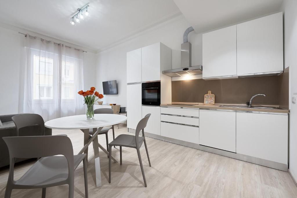 uma cozinha com armários brancos e uma mesa e cadeiras em Casa Flaminia em Roma