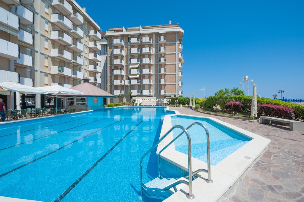 a swimming pool with a hotel in the background at Residence Playa Grande Immobiliare Pacella in Lido di Jesolo